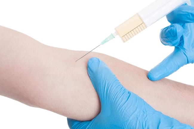 Doctor hands with surgical gloves making injection on male arm